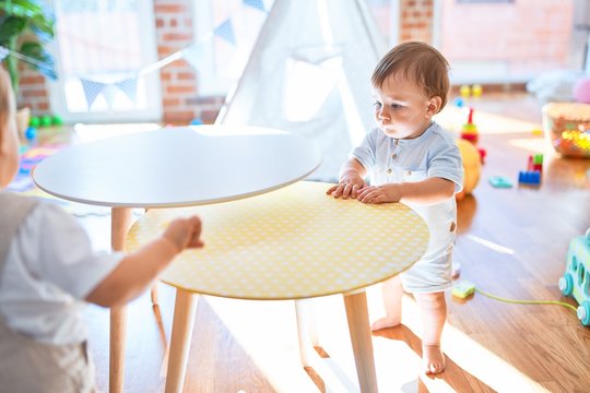 Adorable toddler standing around lots of toys at kindergarten