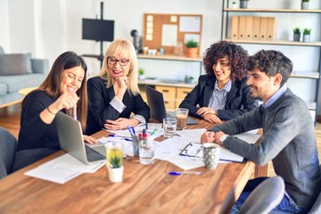 Group of business workers smiling happy and confident. Working together with smile on face  using laptop and speaking at the office