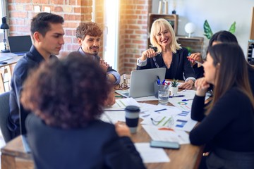 Group of business workers smiling happy and confident. Working together with smile on face  using laptop and speaking at the office