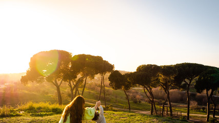 Naklejka premium A pregnant woman is playing with her little son in a park at sunset in Madrid, Spain