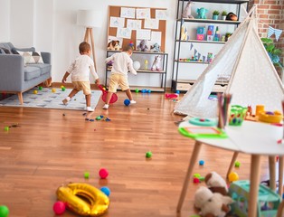 Adorable blonde twins playing around lots of toys at kindergarten