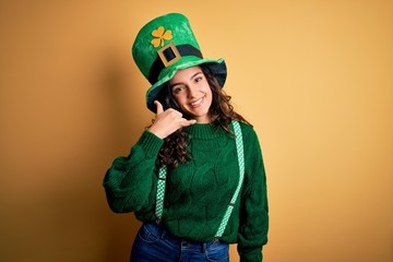 Beautiful curly hair woman wearing green hat with clover celebrating saint patricks day smiling...