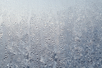 Texture of Frozen drops of condensed steam water drops on the transparent window glass. Clean background. Water vapor condenses on cold window glass and freezes into ice