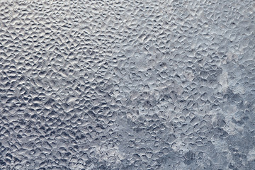Texture of Frozen drops of condensed steam water drops on the transparent window glass. Clean background. Water vapor condenses on cold window glass and freezes into ice