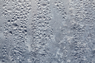 Texture of Frozen drops of condensed steam water drops on the transparent window glass. Clean background. Water vapor condenses on cold window glass and freezes into ice