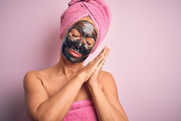 Middle age brunette woman wearing beauty black face mask over isolated pink background sleeping...