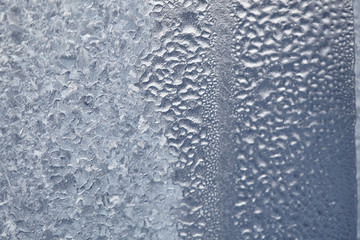 Texture of Frozen drops of condensed steam water drops on the transparent window glass. Clean background. Water vapor condenses on cold window glass and freezes into ice