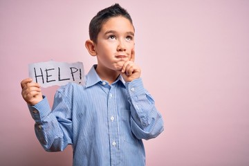 Young little boy kid holding paper sing with help message asking for protection serious face...