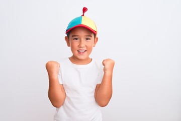 Beautiful kid boy wearing fanny colorful cap with propeller over isolated white background celebrating surprised and amazed for success with arms raised and open eyes. Winner concept. © Krakenimages.com