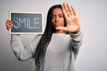 Young african american woman holding blackboard with smile word text over isolated background with...