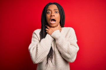 Young african american woman wearing casual winter sweater over red isolated background shouting and suffocate because painful strangle. Health problem. Asphyxiate and suicide concept.