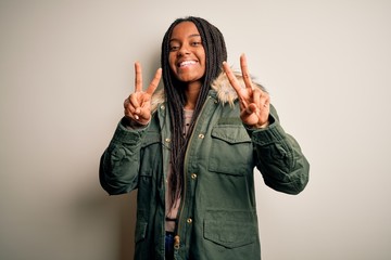 Young african american woman wearing winter parka coat over isolated background smiling looking to...