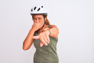 Middle age mature cyclist woman wearing safety helmet over isolated background laughing at you, pointing finger to the camera with hand over mouth, shame expression