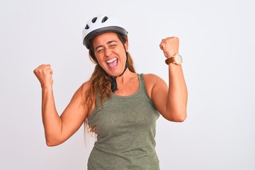 Middle age mature cyclist woman wearing safety helmet over isolated background celebrating surprised and amazed for success with arms raised and eyes closed. Winner concept.