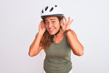 Middle age mature cyclist woman wearing safety helmet over isolated background Trying to hear both hands on ear gesture, curious for gossip. Hearing problem, deaf