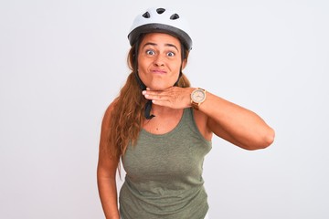 Middle age mature cyclist woman wearing safety helmet over isolated background cutting throat with hand as knife, threaten aggression with furious violence