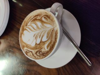 cup of coffee with cream on wooden background