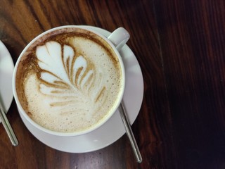 cup of coffee with cream on wooden background