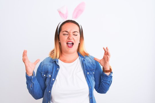 Young beautiful woman wearing banny ears standing over isolated white background celebrating mad and crazy for success with arms raised and closed eyes screaming excited. Winner concept