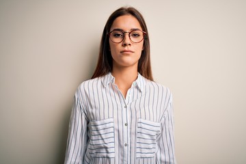 Young beautiful brunette woman wearing casual shirt and glasses over white background Relaxed with serious expression on face. Simple and natural looking at the camera.