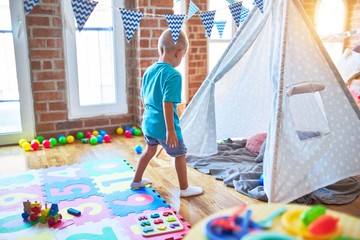 Young caucasian kid playing at kindergarten with toys. Preschooler boy happy at playroom.