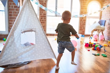 Young caucasian kid playing at kindergarten with toys. Preschooler boy happy at playroom.