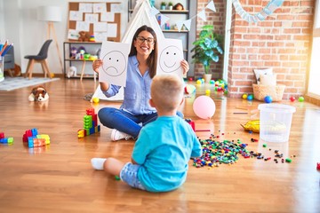Young therapist woman speaking with child, counselor and behaviour correction at the office showing happy and sad face