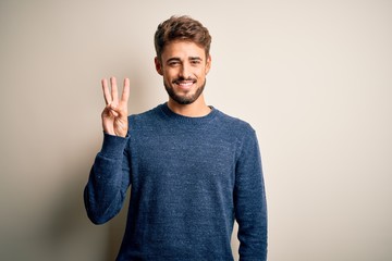 Young handsome man with beard wearing casual sweater standing over white background showing and...