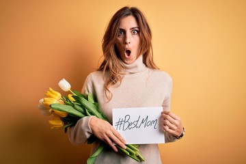 Beautiful brunette woman holding best mom message and tulips celebrating mothers day scared in...