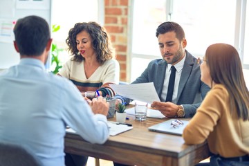 Group of business workers working together. Sitting on desk reading documents at the office