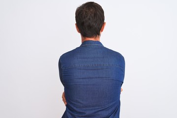 Middle age handsome man wearing blue denim shirt standing over isolated white background standing...