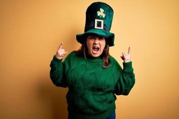 Young beautiful plus size woman wearing green hat with clover celebrating saint patricks day...