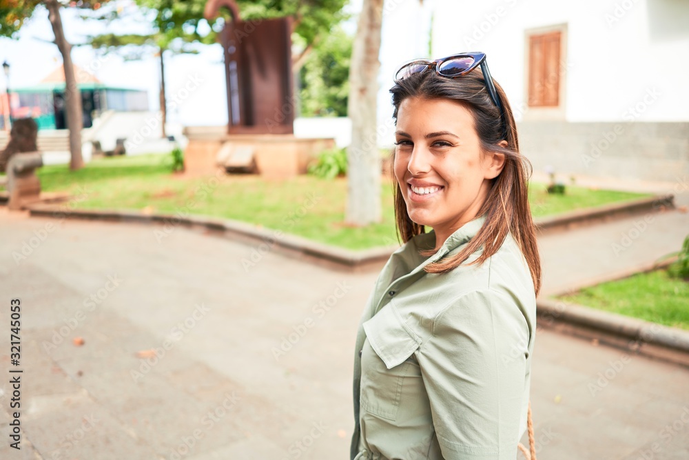 Wall mural Young beautiful woman smiling happy walking on city streets on a sunny day of summer