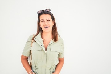 Beautiful girl leaning on white wall, young friendly woman smiling happy on a sunny day of summer