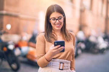 Young beautiful woman smiling happy and confident. Standing with smile on face using smartphone at the city