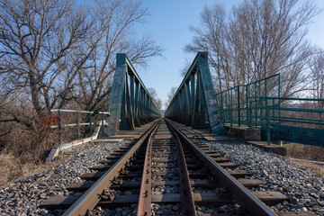 Fototapeta na wymiar Green railroad bridge with tracks over river