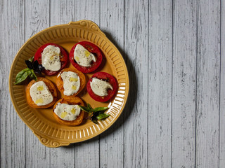 Sliced red and orange tomatoes with mozzarella, olive oil, basil