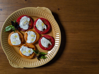 Sliced red and orange tomatoes with mozzarella, olive oil, basil