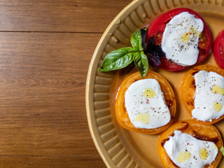 Sliced red and orange tomatoes with mozzarella, olive oil, basil