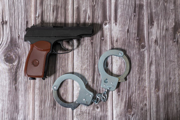 Handcuffs and Makarov gun on dark wooden table. Copy space.