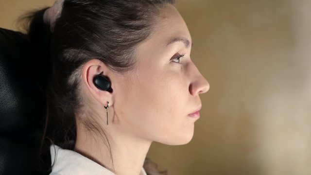 Close-up girl inserts wireless headphones into ears. Single model series