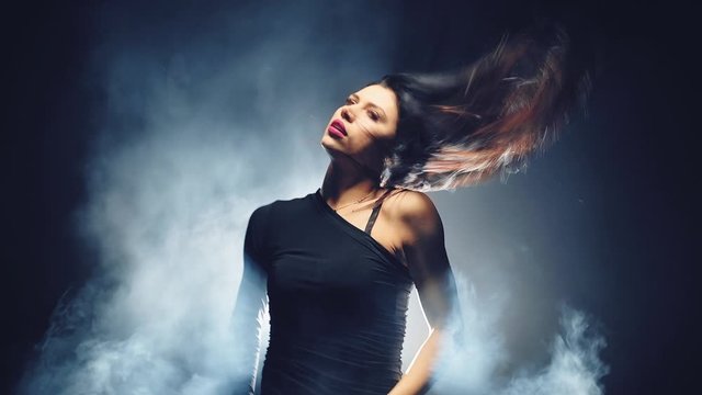 Erotic girl dancing sexy dance with flying hair on smoky background