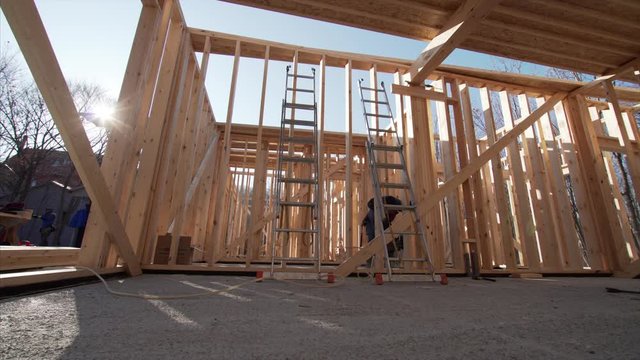 Timelapse view from below of framer attaching beams with hydraylic hammer at frame house building