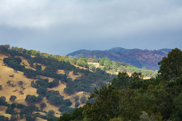 Fototapeta premium Light through the clouds lighting up mountain face lake berryessa california.