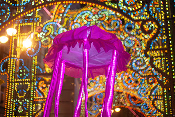Festive masquerade. Glowing jellyfish in the form of an umbrella. Night city life for a holiday. Entertaining citizens with vibrant objects. A jellyfish made of fabric and placed on a pole. 