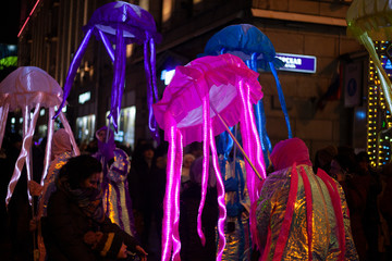 Festive masquerade. Glowing jellyfish in the form of an umbrella. Night city life for a holiday. Entertaining citizens with vibrant objects. A jellyfish made of fabric and placed on a pole.