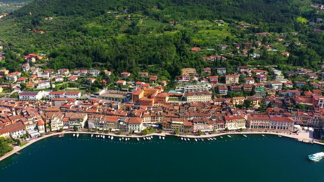Flying over the city of Salo, Lake Garda, Italy. Against the background of the historical part of the city, blue sky, mountains. Aerial view	