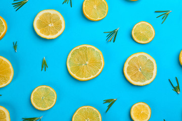 Lemonade layout with juicy lemon slices and rosemary on blue background, top view