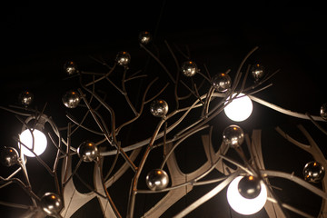 Beautiful lamps. Designer lights. Metal balls as an element of decor. Beautiful interior. Dark background with bright lamps on curved steel racks.