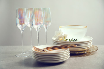 Set of glasses and dishes with flowers on light grey table